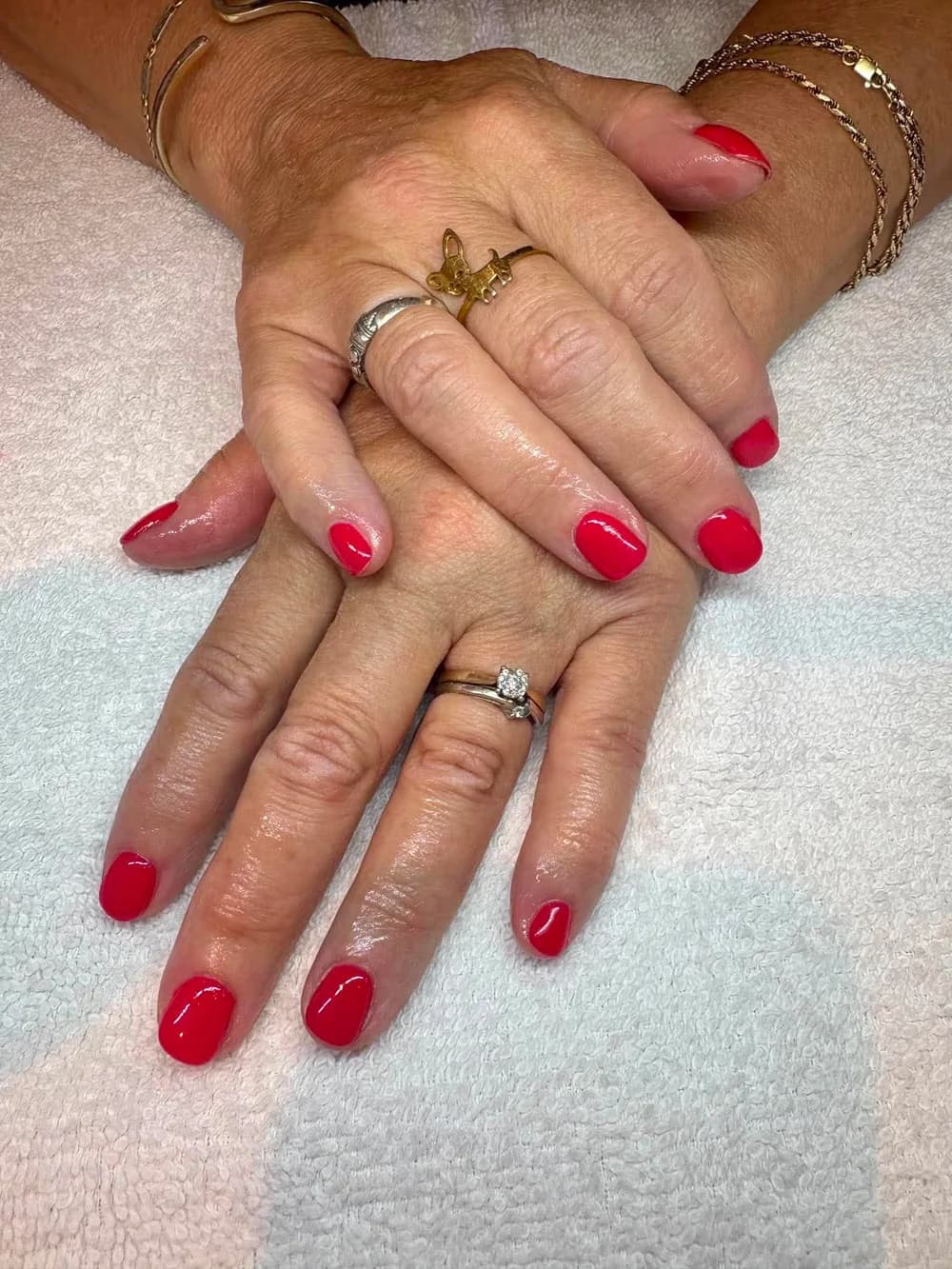 Manucure au vernis gel rouge vif sur des ongles courts et arrondis, réalisée chez Éclat Esthétique